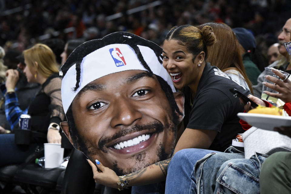 Kamiah Adams-Beal holds a photo of her husband, Washington Wizards guard Bradley Beal, during the second half of an NBA basketball game against the Toronto Raptors, Saturday, March. 4, 2023, in Washington. (AP Photo/Terrance Williams)