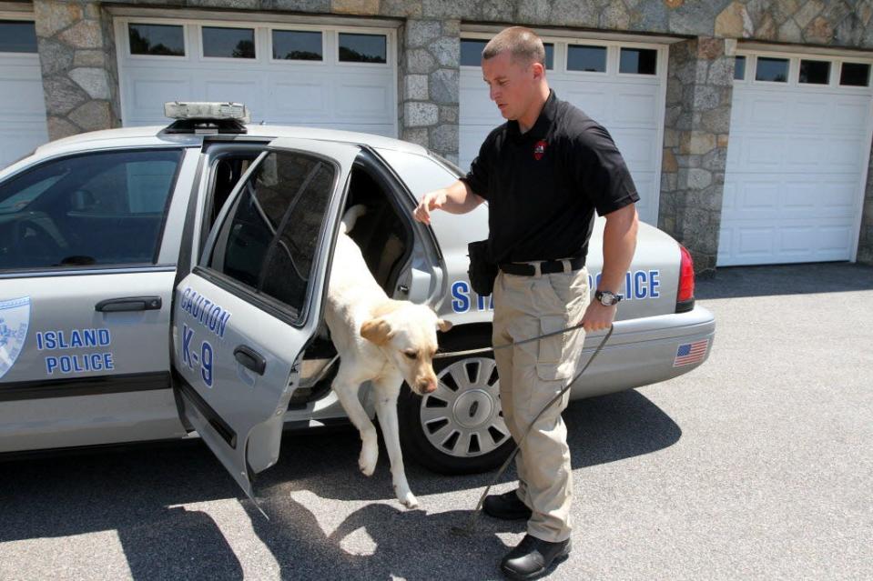 Det. Adam Houston takes Thoreau from his cruiser to the training office at State Police Headquarters in Scituate in 2014.