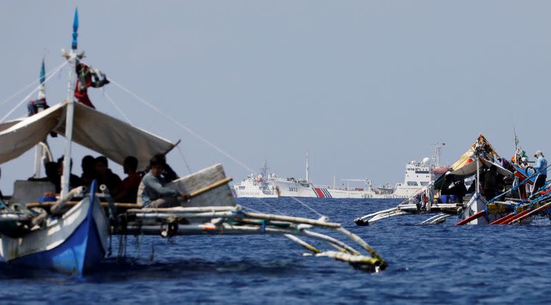 FILE PHOTO: China Coast Guard vessels patrol past Philippine fishing boats at the disputed Scarborough Shoal