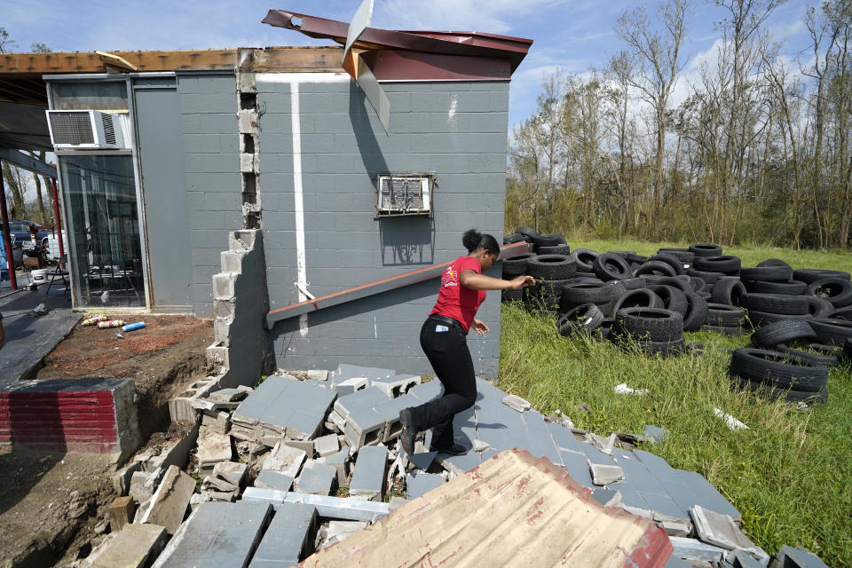 Layla Winbush walks over the debris of her family's destroyed auto detailing business in Lake Charles, La., in the aftermath of Hurricane Laura, Sunday, Aug. 30, 2020. (AP Photo/Gerald Herbert)