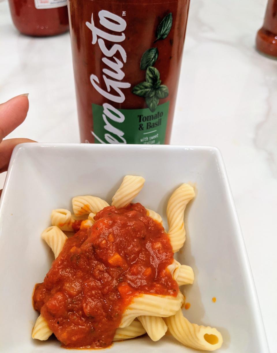 Jar of vero gusto red sauce behind a small white bowl of pasta