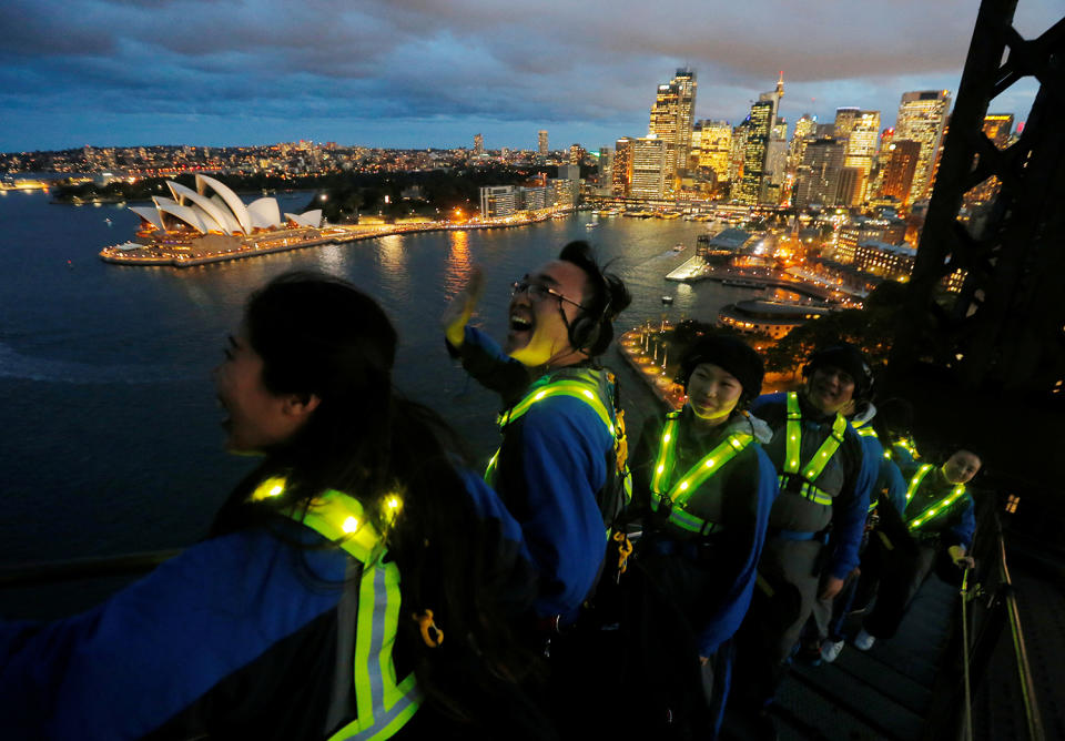 Participants wear glowing vests as they look out to the Sydney Opera House