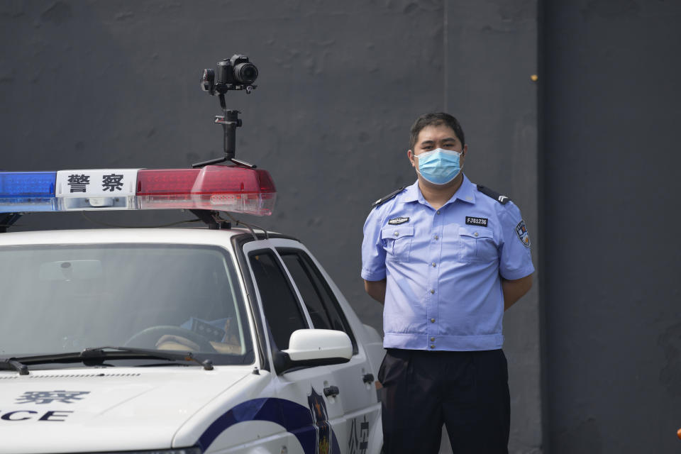 A policeman wearing a face mask stands guard next to a police vehicle with a camera outside a detention center where Dominic Barton, Ambassador of Canada to China will meet Canadian Michael Spavor, in Dandong, China, Wednesday, Aug. 11, 2021. A Chinese court has sentenced Michael Spavor to 11 years on spying charges in case linked to Huawei. (AP Photo/Ng Han Guan)