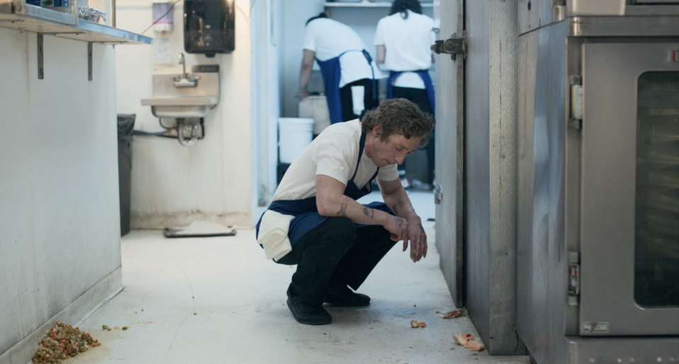 Carmy squatting down in the kitchen