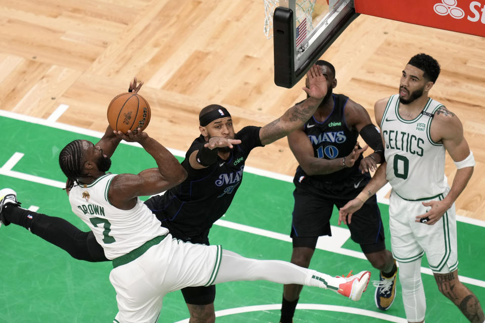 Boston Celtics guard Jaylen Brown, left, shoots as Dallas Mavericks center Daniel Gafford, center left, defends in front of Mavericks forward Tim Hardaway Jr., center right, and Celtics forward Jayson Tatum during the second half of Game 1 of basketball's NBA Finals on Thursday, June 6, 2024, in Boston. (AP Photo/Michael Dwyer)