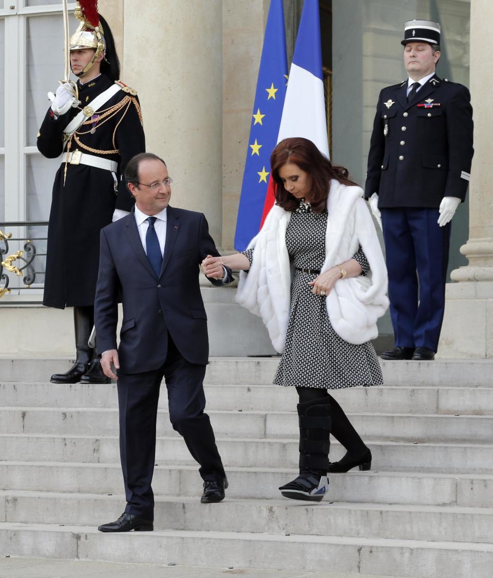 French President Francois Hollande, left, aids Argentine President Cristina Fernandez as she leaves after a press conference at the Elysee Palace in Paris, Wednesday, March 19, 2014. Fernandez met French counterpart and discussed ways to tackle her country's growing international debt. Fernandez injured her foot during her visit to Italy earlier this week. (AP Photo/Christophe Ena)