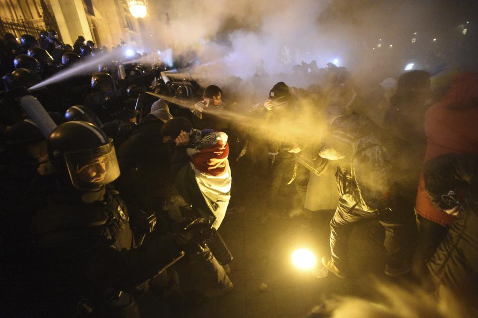 Protesters clash with police during a demonstration against the amendments to the labour code, dubbed "slave law" by oppositional forces, at the parliament building in Budapest, Thursday, Dec. 13, 2018. Thursday's evening rally was called to oppose recent changes to the labor code which unions and critics say will hurt workers and protesters shouted slogans against Prime Minister Viktor Orban. Some protesters threw bottles and smoke bombs at police in riot gear guarding the neo-Gothic national legislature.(Zoltan Balogh/MTI via AP)