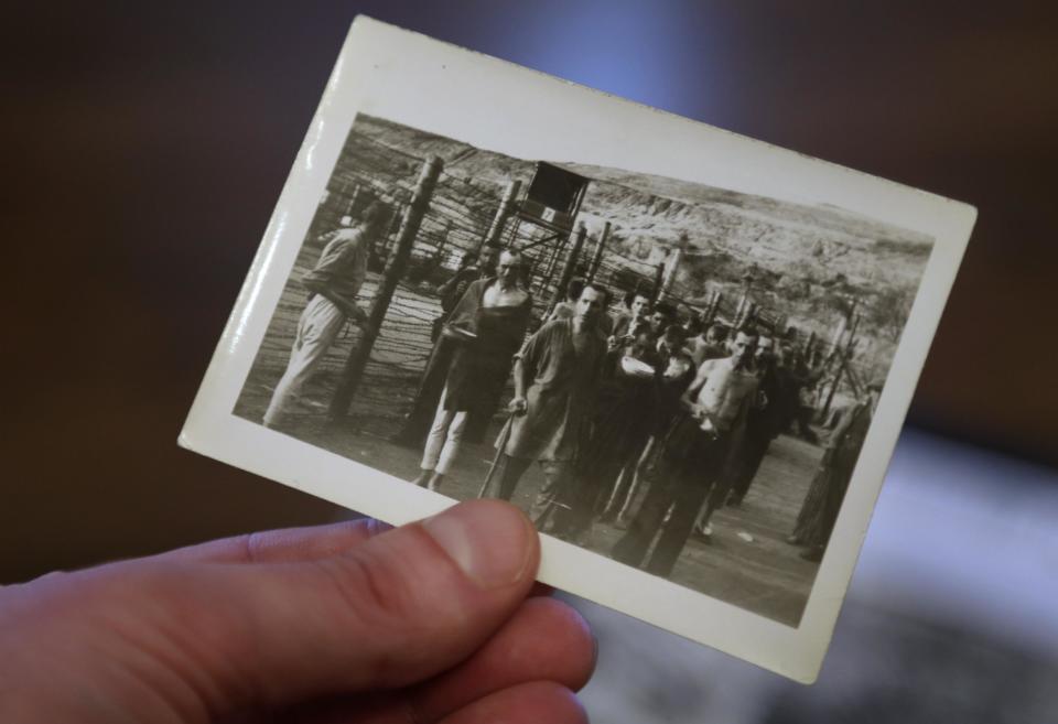 In this Tuesday, April 2, 2013 photo filmmaker Matthew Nash, hand only, holds a 1945 photograph, in his Boston home, that shows survivors at what is believed to be the Nazi Mauthausen concentration camp. The photo was taken by Nash's grandfather U.S. Army medic Donald Johnson. Nash's discovery of photographs by his grandfather led him to create a documentary about the liberation of the Ohrdruf concentration camp in Germany, the first that the Americans found. (AP Photo/Steven Senne)