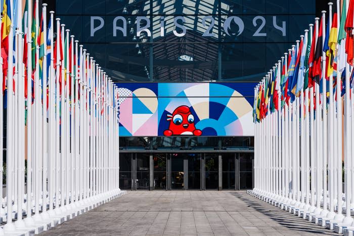 Multiple international flags line a path leading to a building with 