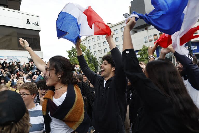 La gente ondea banderas francesas mientras reacciona a los resultados proyectados después de la segunda vuelta de las elecciones legislativas, el domingo 7 de julio de 2024 en Nantes, oeste de Francia.