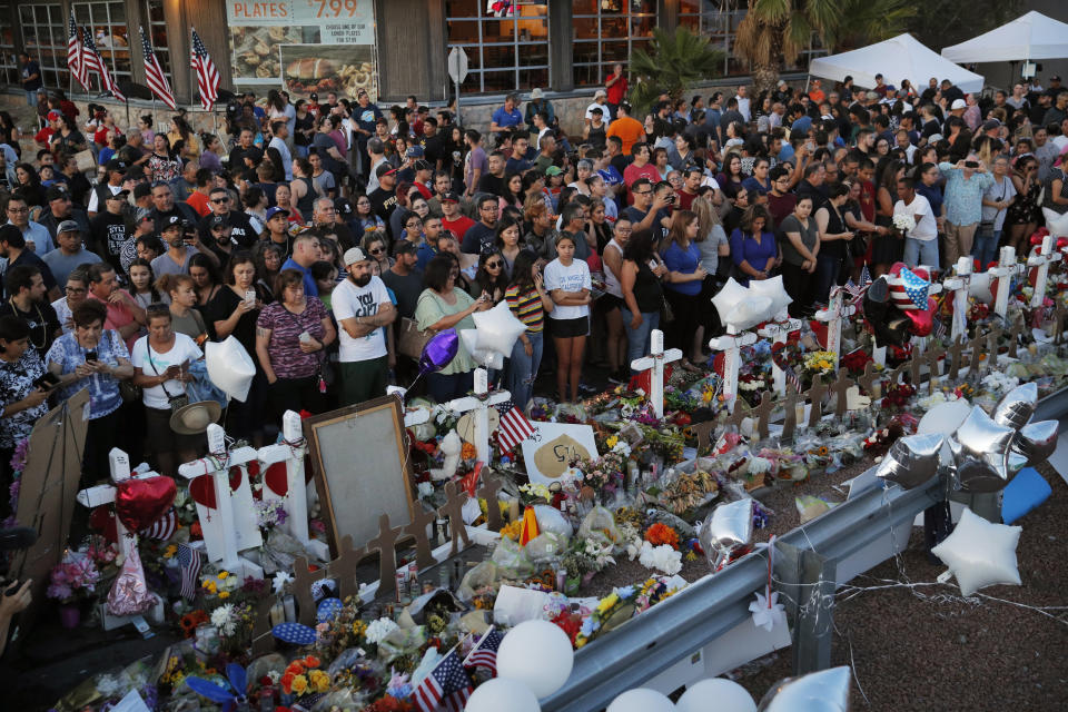 FILE - In this Aug. 6, 2019, file photo, people crowd around a makeshift memorial at the scene of a mass shooting at a shopping complex in El Paso, Texas. In the days and weeks since three high-profile shootings took the lives of more than two dozen people in just a week's time, law enforcement authorities have reported seeing a spike in the number of tips they are receiving from concerned relatives, friends and co-workers of people who appear bent on carrying out the next mass shooting. (AP Photo/John Locher, File)