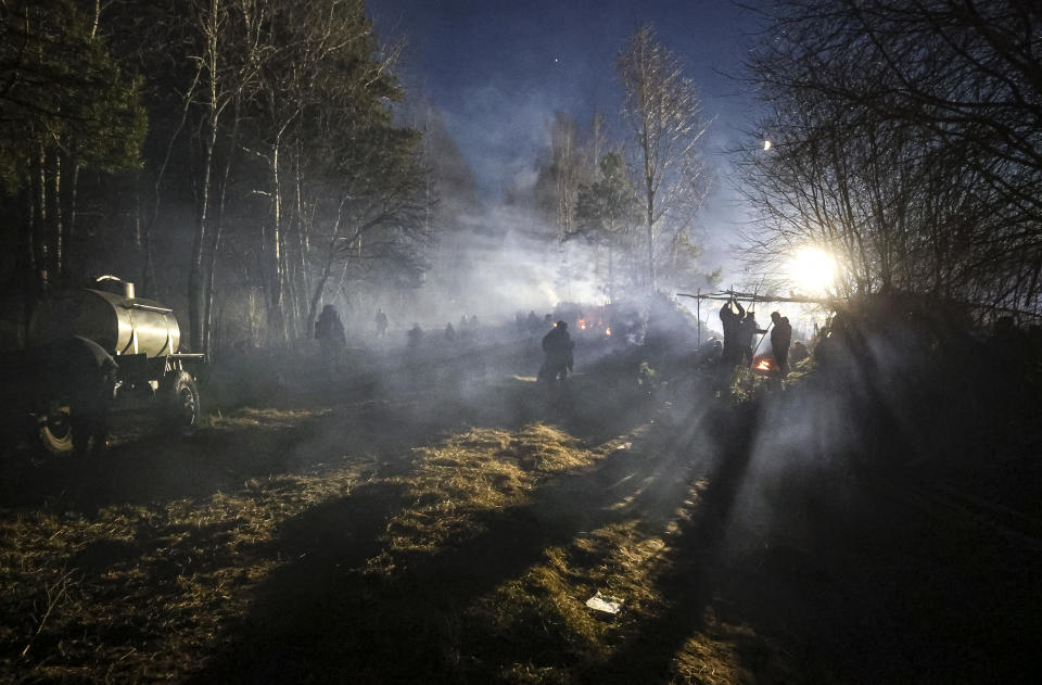 Migrants walk at a tent camp set by migrants from the Middle East and elsewhere gathering at the Belarus-Poland border near Grodno, Belarus, late Wednesday, Nov. 10, 2021. The European Union has accused Belarus' authoritarian President Alexander Lukashenko of encouraging illegal border crossings as a "hybrid attack" to retaliate against EU sanctions on his government for its crackdown on internal dissent after Lukashenko's disputed 2020 reelection. (Ramil Nasibulin/BelTA pool photo via AP)
