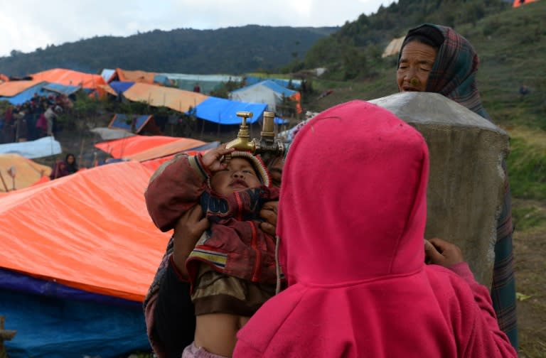 Children try to get water from a tap in a makeshift settlement at Laprak village, Nepal's northern-central Gorkha district