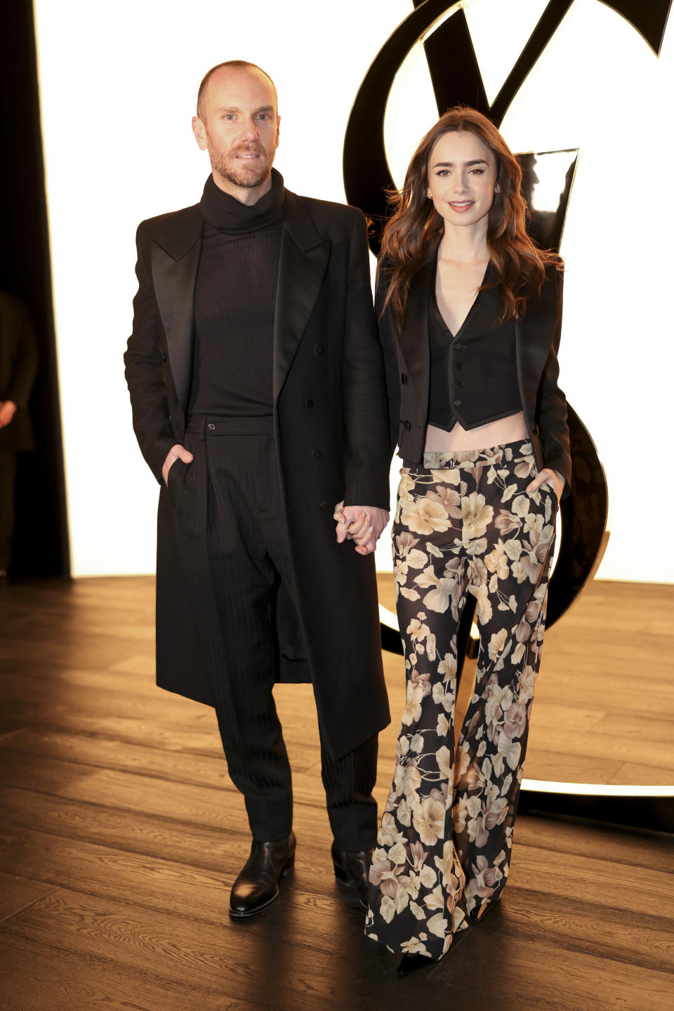Charlie McDowell , left, and Lily Collins attend the Yves Saint Laurent Fall/Winter 2024-2025 ready-to-wear collection presented Tuesday, Feb. 27, 2024 in Paris. (Photo by Vianney Le Caer/Invision/AP)