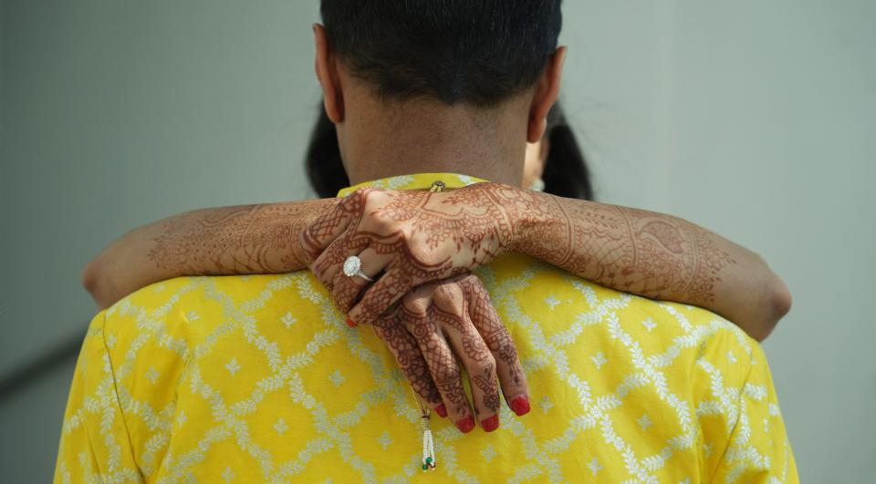 With her hands covered in Mehndi, a temporary skin decoration using a paste created with henna, Rupal Ramesh Shah hugs her husband, Anup Kumar Kanodia, during a morning photo session on June 9 at the Hyatt Regency. The henna artist, Kunjal Patel, spent about three hours creating the designs on Shah's arms and hands.