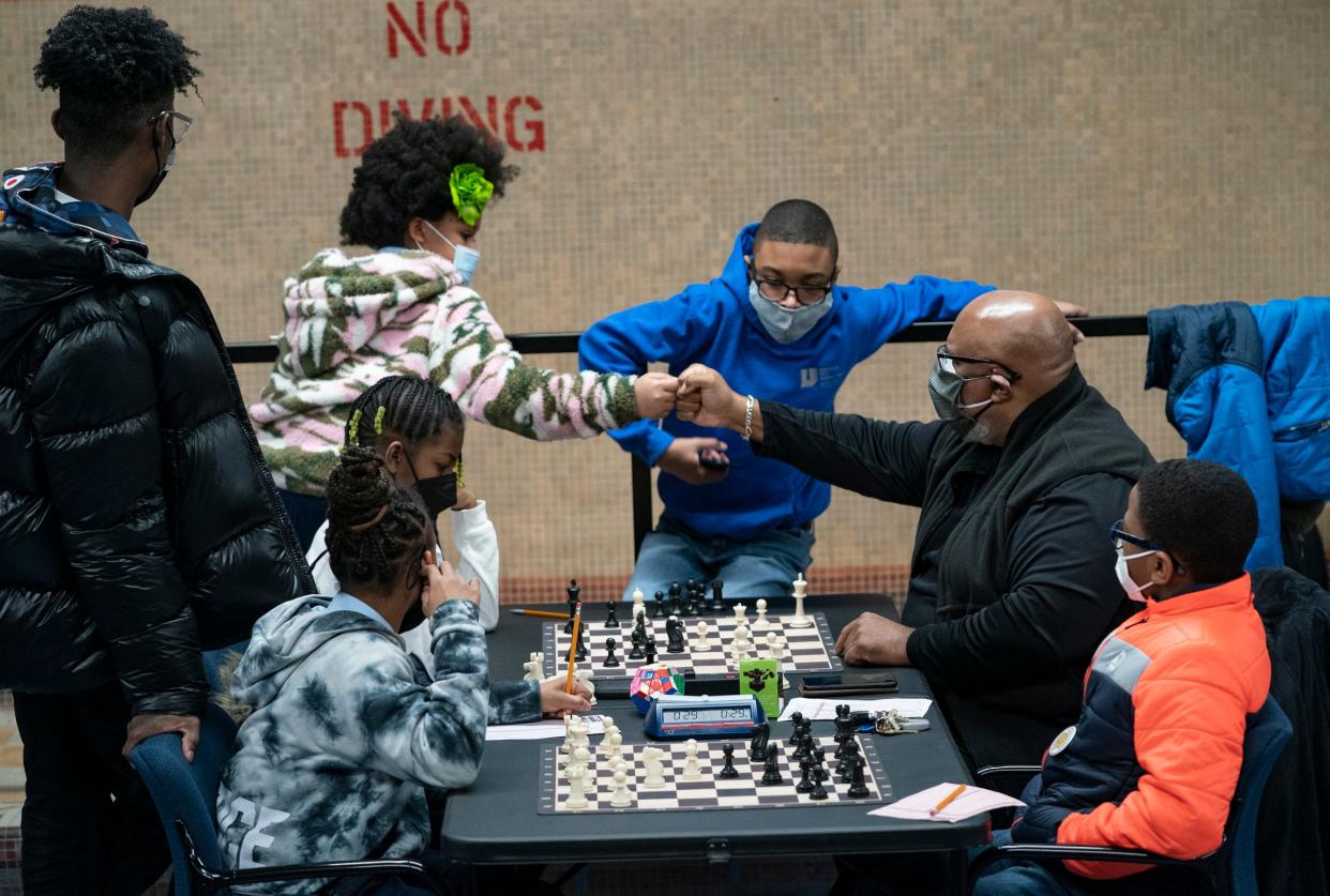 Kymoni Brown, 9, of Detroit, left, fist bumps her coach Kevin Fite as he instructs students on their chess moves Friday, March 18, 2022, at the Durfee Innovation Society in Detroit. Fite founded the Detroit City Chess Club after taking his inspiration from Fox 2 anchor Huel Perkins who helped Fite return to college after dropping out. The only repayment Perkins wanted from Fite was for Fite to pay those actions forward.