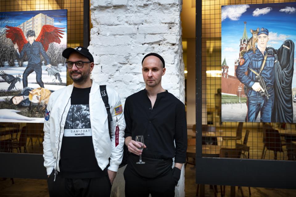 In this photo taken on Saturday, Oct. 26, 2019, the Gogol center director Kirill Serebrennikov, left, and painter Pasmur Rachuiko, who offers an extreme outsider's view of Moscow reality pose for a photo in the Gogol Center in Moscow, Russia. Moscow’s suburbs are the focus of a major international art exhibition that has just opened in the Russian capital. The exhibit uses contemporary art to explore the many hidden facets of life beyond the Russian capital’s nucleus. Austrian cultural attache says the ‘real’ Moscow where most of the city’s 12.6 million people live, is outside the center.(AP Photo/Alexander Zemlianichenko)