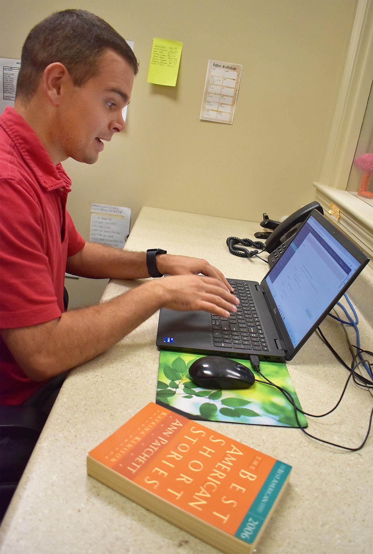 Sam Freitas checks out a book at the Infinity Library at People, Incorporated on Thursday, Aug. 8, 2024. The library is designed by and for neurodiverse people.