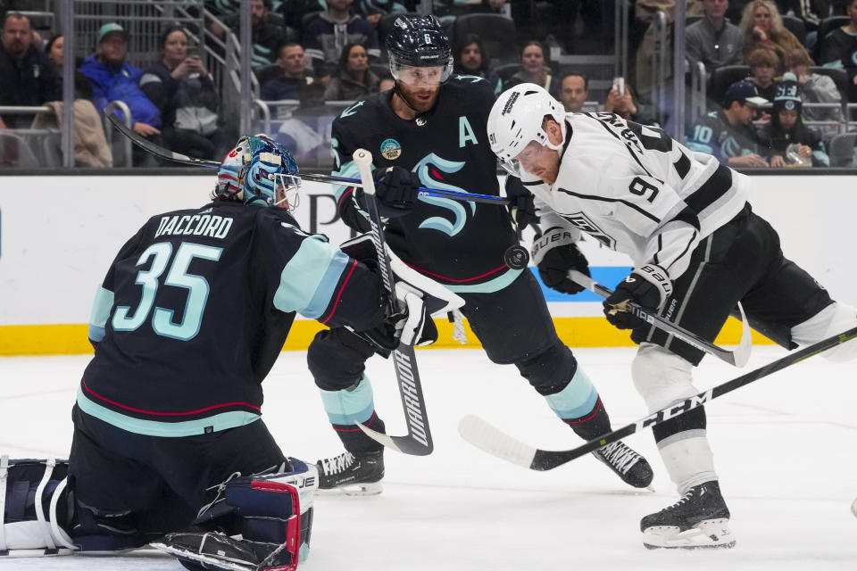 Los Angeles Kings right wing Carl Grundstrom (91) looks down at the puck as it flies up in front of him while trying to make a shot against Seattle Kraken goaltender Joey Daccord (35) and defenseman Adam Larsson (6) during the second period of an NHL hockey game Saturday, Dec. 16, 2023, in Seattle. (AP Photo/Lindsey Wasson)