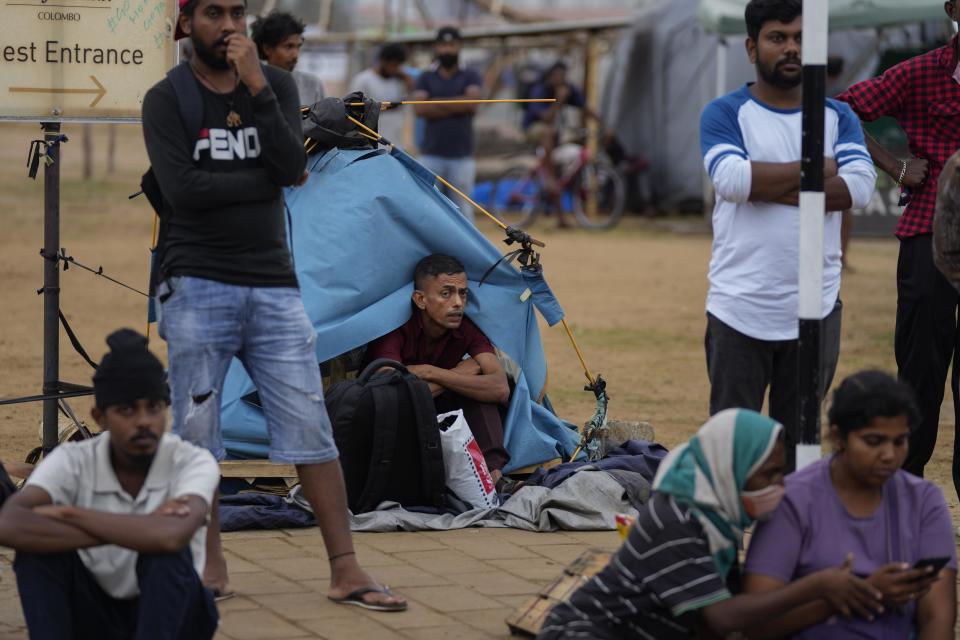 Protesters wait and watch troops stand guard following an eviction of protesters from the presidential secretariat in Colombo, Sri Lanka, Friday, July 22, 2022. (AP Photo/Eranga Jayawardena)