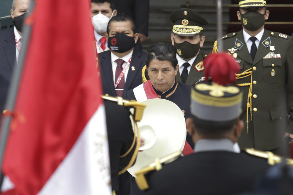 Peru's newly sworn-in President Pedro Castillo removes his hat momentarily to acknowledge the Peruvian flag held by soldiers outside Congress on his inauguration day in Lima, Peru, Wednesday, July 28, 2021. (AP Photo/Francisco Rodriguez)