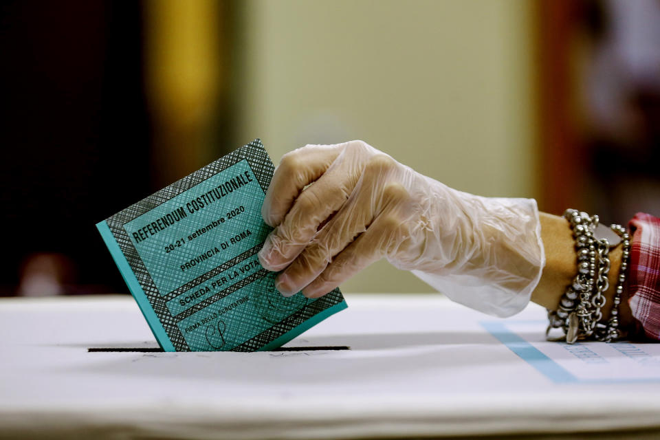 A woman casts her ballot at a polling station, in Rome, Monday, Sept. 21, 2020. On Sunday and Monday Italians are called to vote nationwide in a referendum to confirm a historical change to the country's constitution to drastically reduce the number of Members of Parliament from 945 to 600. Eighteen million of Italian citizens will also vote on Sunday and Monday to renew local governors in seven regions, along with mayors in approximately 1,000 cities. (Cecilia Fabiano/Lapresse via AP)