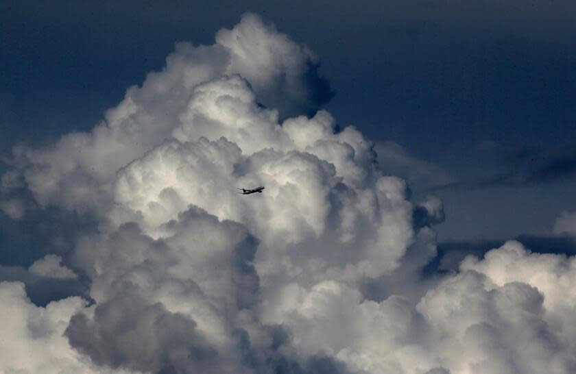 Long Beach, CA - Heavy clouds serve as a backdrop for a plane flying over the Los Angeles Basin on Friday, Dec. 22, 2023. A recent storm dropped up to seven inches of rain on some parts of Southern California. . (Luis Sinco / Los Angeles Times)