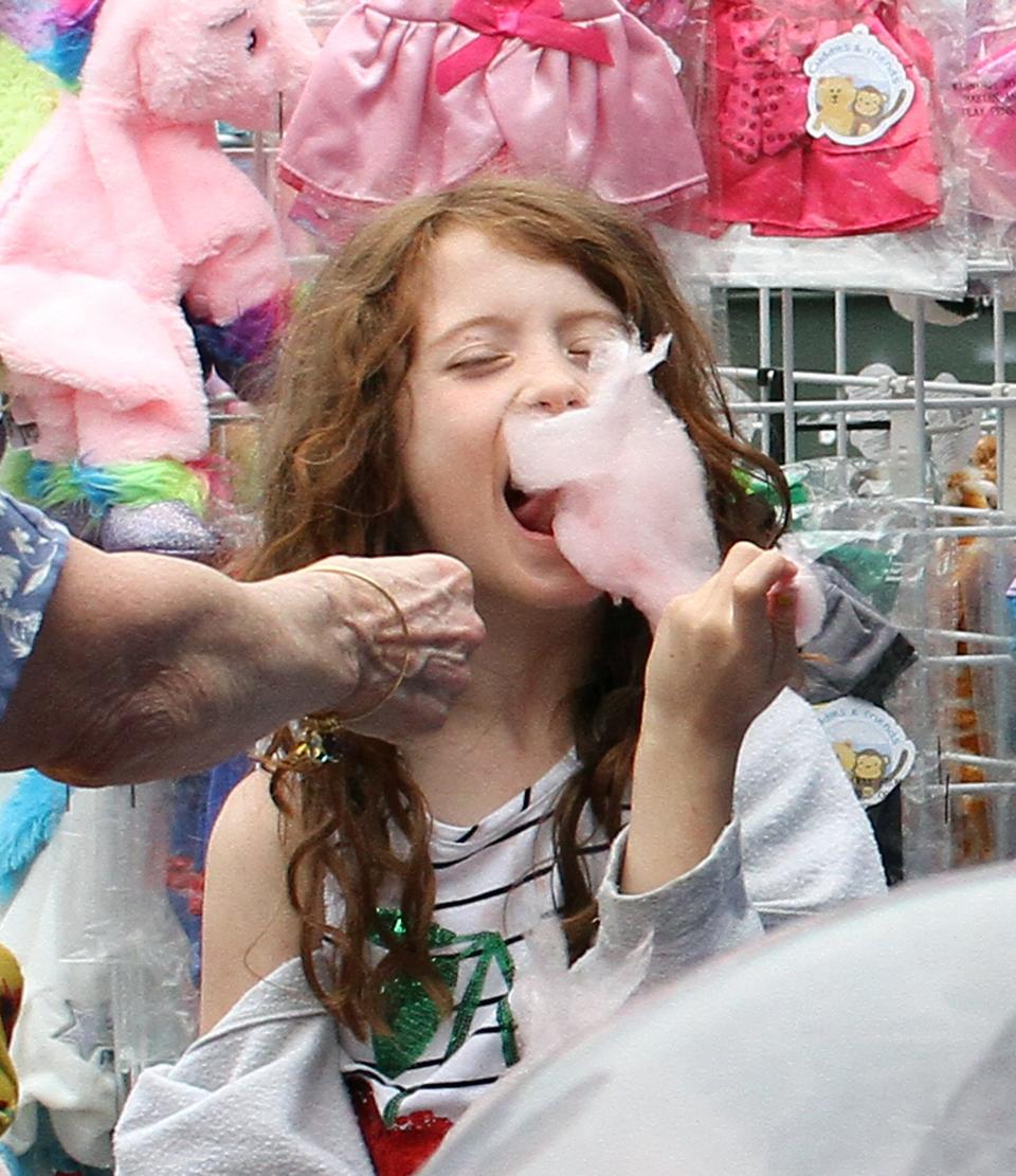 A young girl takes a bite out of her cotton candy at Strawberry Fest on Saturday, May 8, 2021.