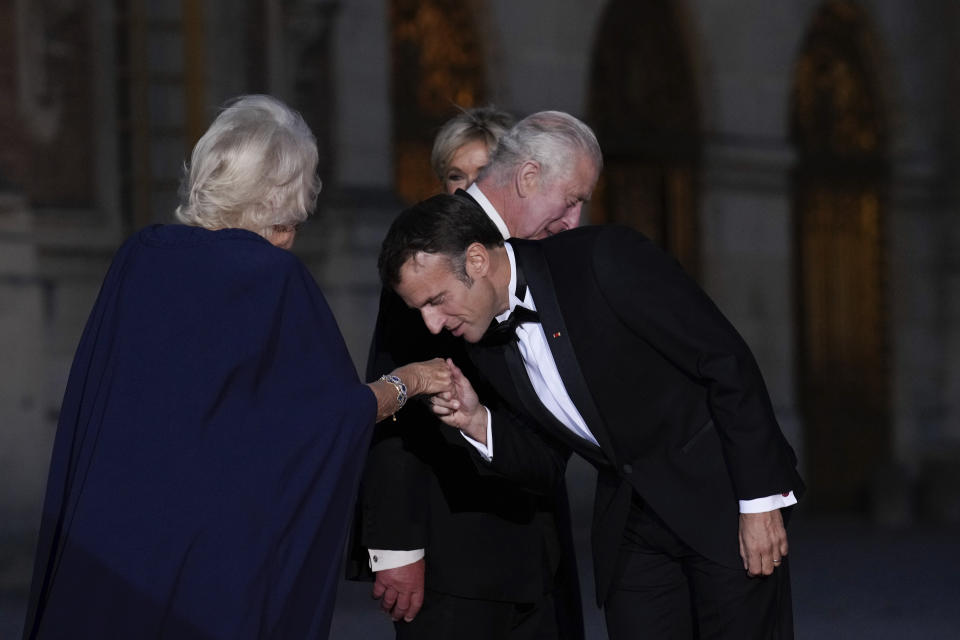 French President Emmanuel Macron kisses Britain's Queen Camilla hand as they arrive for a state dinner, at the Chateau de Versailles, west of Paris, Wednesday, Sept. 20, 2023. King Charles III of the United Kingdom starts a three-day state visit to France on Wednesday meant to highlight the friendship between the two nations with great pomp, after the trip was postponed in March amid widespread demonstrations against President Emmanuel Macron's pension changes. (AP Photo/Christophe Ena)