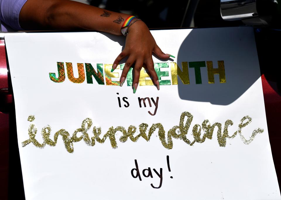 Demory Bonilla holds down a sign as the Juneteenth parade waits to get underway Saturday.