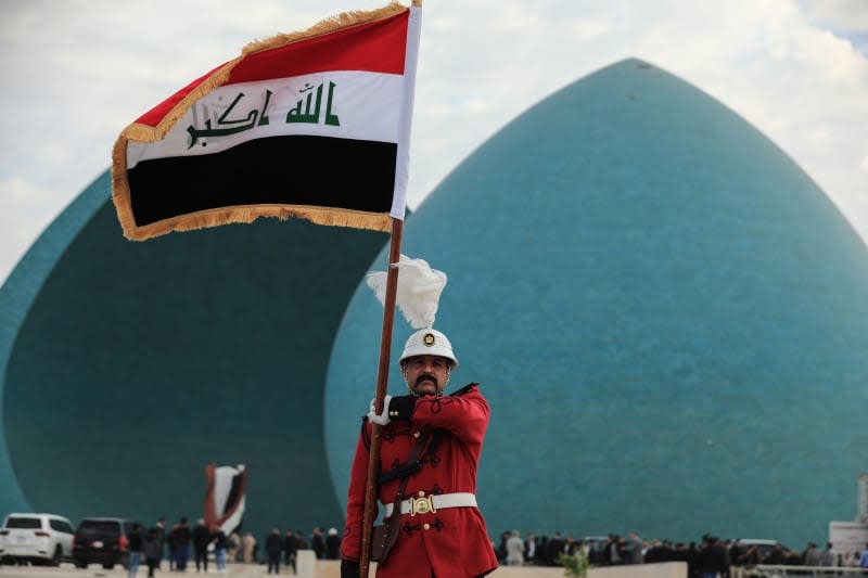 A soldier holds the Iraqi flag as the remains of 41 Yazidis, who were found in a mass grave in the Sinjar district, are transported during a funeral ceremony at the Martyr’s Monument in Baghdad. ISIS killed them during the fall of Mosul in mid-2014. Ameer Al-Mohammedawi/dpa