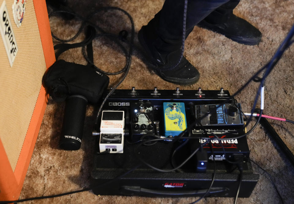 CORRECTS TO TWO SEMESTERS, NOT ONE - Santos Enrique Camara, who dropped out of Shoreline Community College at age 19 in 2015 after completing two semesters studying audio engineering, stands next to a pedal board while practicing with his band The Lion & The Sloth at his home Thursday, March 23, 2023, in Marysville, Wash. Camara, now 27, had difficulty paying tuition and finding time to do schoolwork while caring for his younger sister. "I seriously tried," he said. "I gave it my all." For now, Camara is happy working as a sous-chef and cook at a local restaurant while planning a tour with one of his two bands. (AP Photo/Lindsey Wasson)