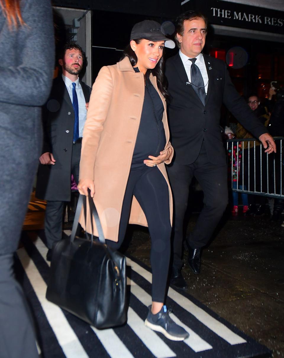 <p>The Duchess of Sussex was spotted leaving her hotel to return home to London. The royal mom-to-be sported a casual and low-key look that included a camel coat, a black zip-up athletic shirt, leggings, sneakers, baseball cap, and leather tote bag. </p>