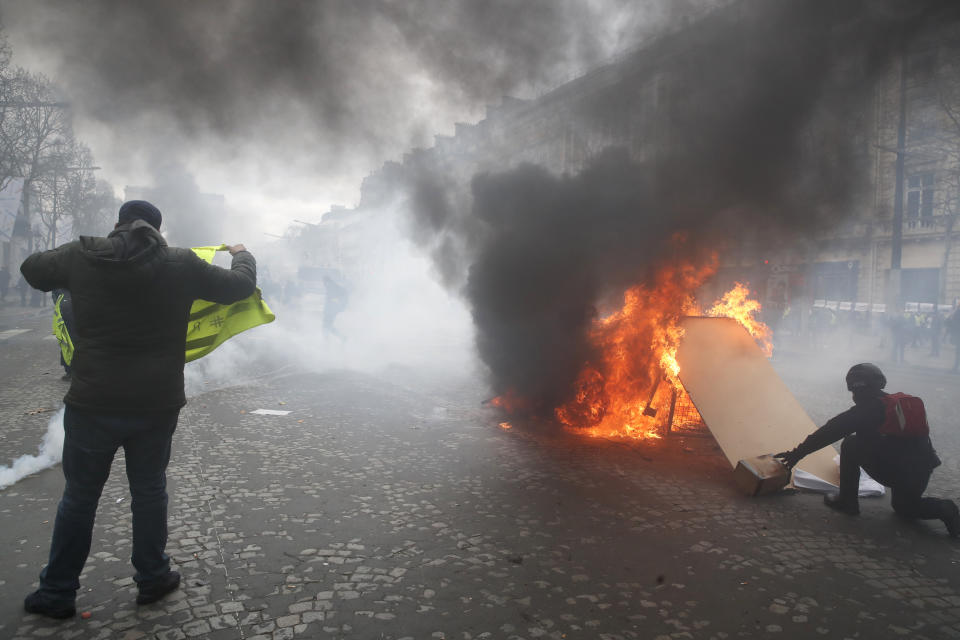 Yellow vests protesters set a burricade afire on the Champs Elysees avenue Saturday, March 16, 2019 in Paris. French yellow vest protesters clashed Saturday with riot police near the Arc de Triomphe as they kicked off their 18th straight weekend of demonstrations against President Emmanuel Macron. (AP Photo/Christophe Ena)