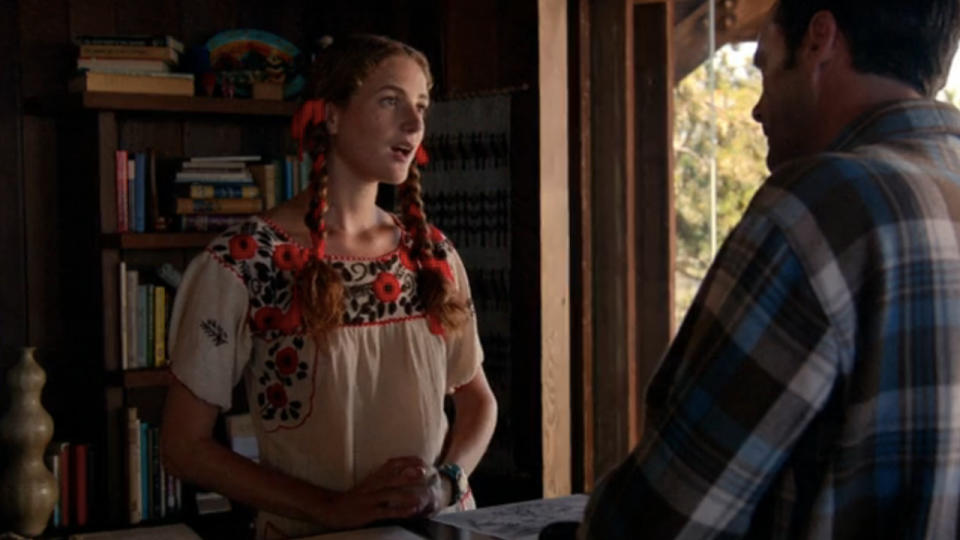 Anna Osceola speaks with Jon Hamm at a reception desk in Mad Men.