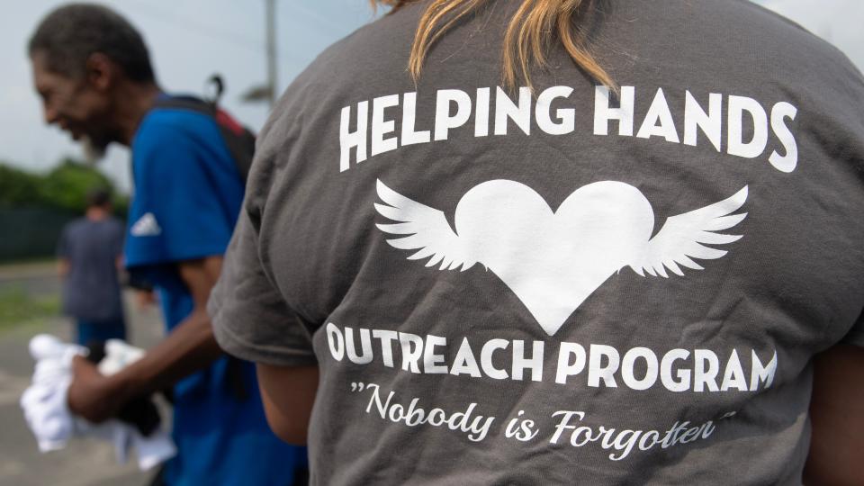 “Country,” who has been on the streets of Camden off and on for two decades, receives socks from members of the Helping Hands Outreach Program in Camden on July 18, 2023.  