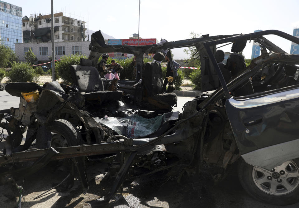 Afghan security personnel inspect the site of a bomb explosion in Kabul, Afghanistan, Thursday, June 3, 2021. Police say a bomb has ripped through a minivan in the western part of the Afghan capital Kabul, killing at least four people. No one took responsibility for the attack in the neighborhood, which is largely populated by the minority Hazara ethnic group who are mostly Shiite Muslims. (AP Photo/Rahmat Gul)