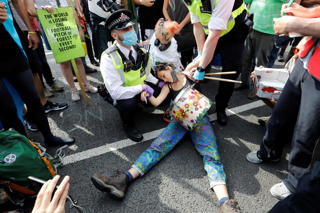 Police officers wearing face masks and gloves due to the COVID-19 pandemic, detain an activist from the climate protest group Extinction Rebellion as they demonstrate in Parliament Square in London on September 2, 2020, on the second day of their latest season of 