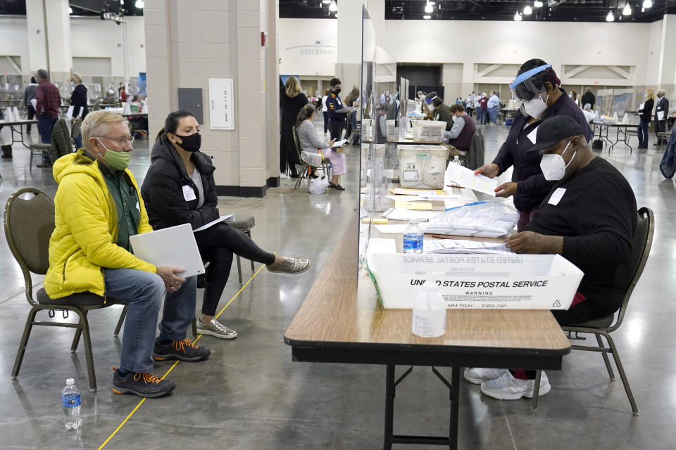 FILE - In this Nov. 20, 2020, file photo, election workers, right, verify ballots as recount observers, left, watch during a Milwaukee hand recount of presidential votes at the Wisconsin Center in Milwaukee. President Donald Trump filed a lawsuit Tuesday, Dec. 1, 2020, in Wisconsin seeking to disqualify hundreds of thousands of ballots in a longshot attempt to overturn Democrat Joe Biden's win in the battleground state he lost by nearly 20,700 votes. (AP Photo/Nam Y. Huh File)