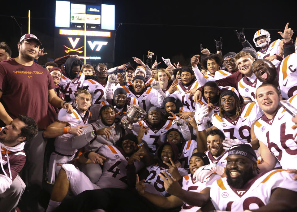 Virginia Tech players pose for a photograph after a win over Virginia in an NCAA college football game Saturday, Nov. 27, 2021, in Charlottesville, Va. (Matt Gentry/The Roanoke Times via AP)