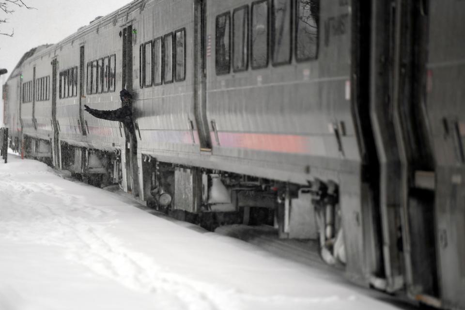 A New Jersey Transit employee signals as a Hoboken-bound train crosses through the Rutherford station as snow falls on Super Bowl Sunday on February 7, 2021.