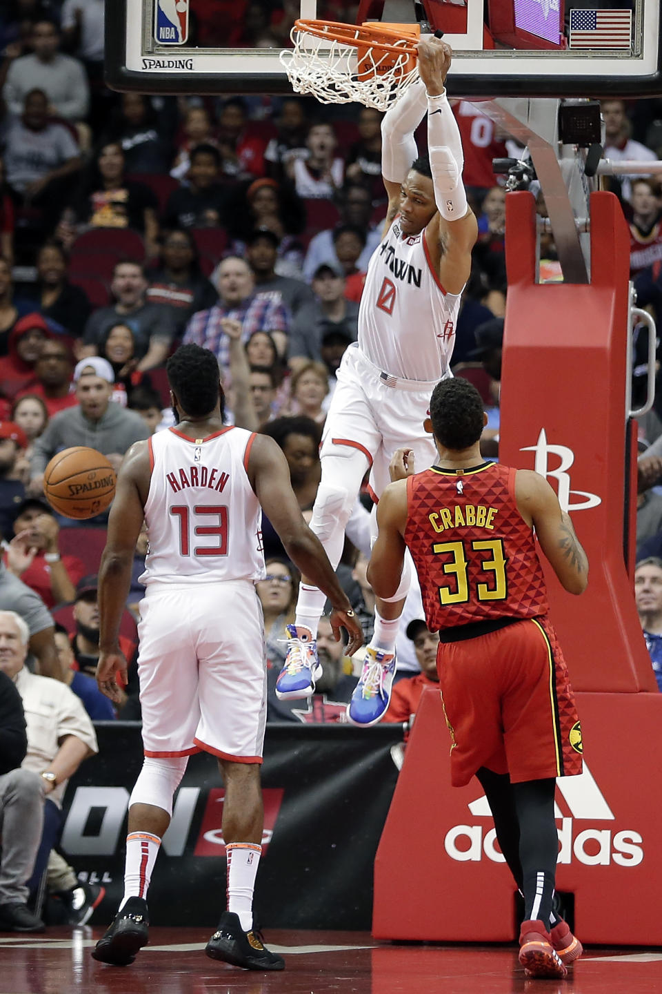 Houston Rockets guard Russell Westbrook (0) hangs on the rim after his dunk as James Harden (13) and Atlanta Hawks guard Allen Crabbe (33) look on during the first half of an NBA basketball game, Saturday, Nov. 30, 2019, in Houston. (AP Photo/Michael Wyke)