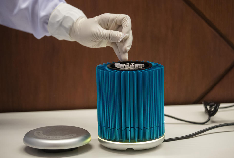 A laboratory staff member demonstrates testing for the COVID-19 virus at Suvarnabhumi Airport in Bangkok, Friday, July 3, 2020. As the country starts to ease its travel restrictions allowing foreign visitors in on a controlled basis, the lab will have the results ready within 90 minutes for arriving travelers. (AP Photo/Sakchai Lalit)