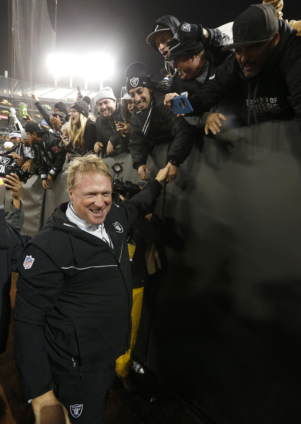 Oakland Raiders head coach Jon Gruden, left, smiles after greeting fans after an NFL football game against the Denver Broncos in Oakland, Calif., Monday, Dec. 24, 2018. (AP Photo/D. Ross Cameron)