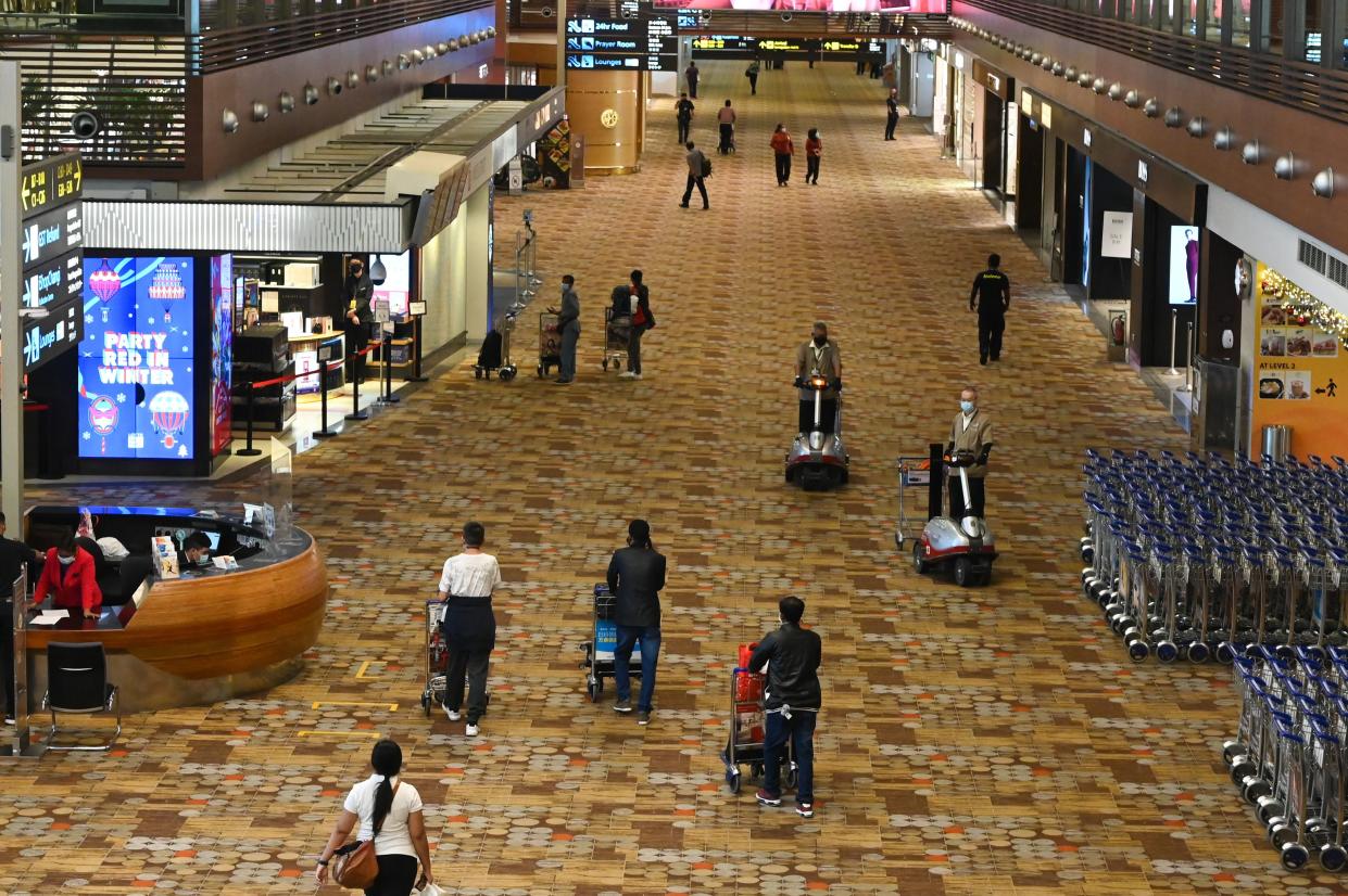 People walk along the transit hall at Changi International Airport in Singapore on January 7, 2021. (Photo by Roslan Rahman / AFP) (Photo by ROSLAN RAHMAN/AFP via Getty Images)