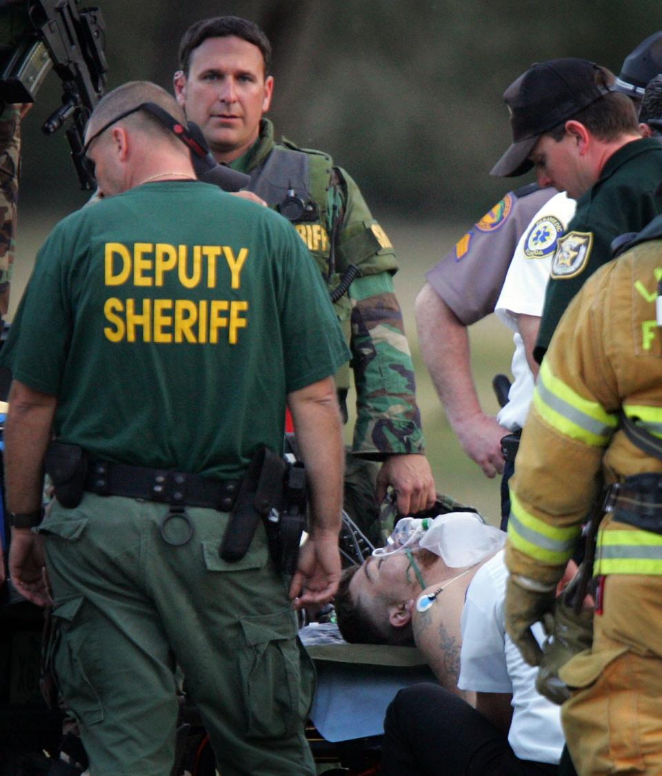 Jason Lee Wheeler lies on a stretcher surrounded by law enforcement after he was captured Wednesday evening February 9, 2005. Wheeler was flown out on Omniflight from a pasture near the Paisley Fire Department. Wheeler had shot an killed Lake County Sheriff's Deputy Wayne Koester and wounded two other officers at his home in Paisley, FL Wednesday morning February 9, 2005 when they arrived to a domestic dispute call.