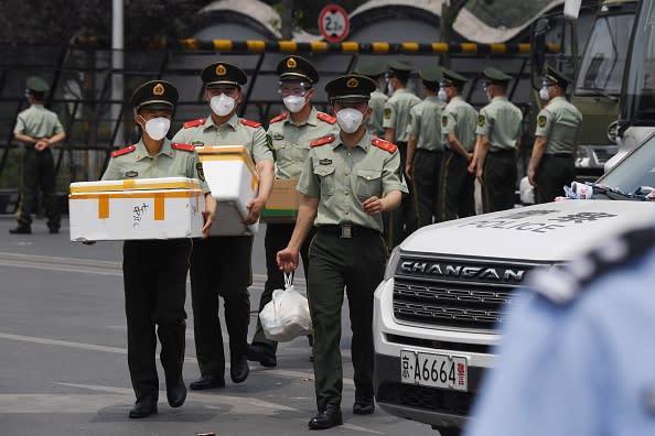 Paramilitary police officers wear face masks as they prepare food supplies at the entrance to the closed Xinfadi market in Beijing.