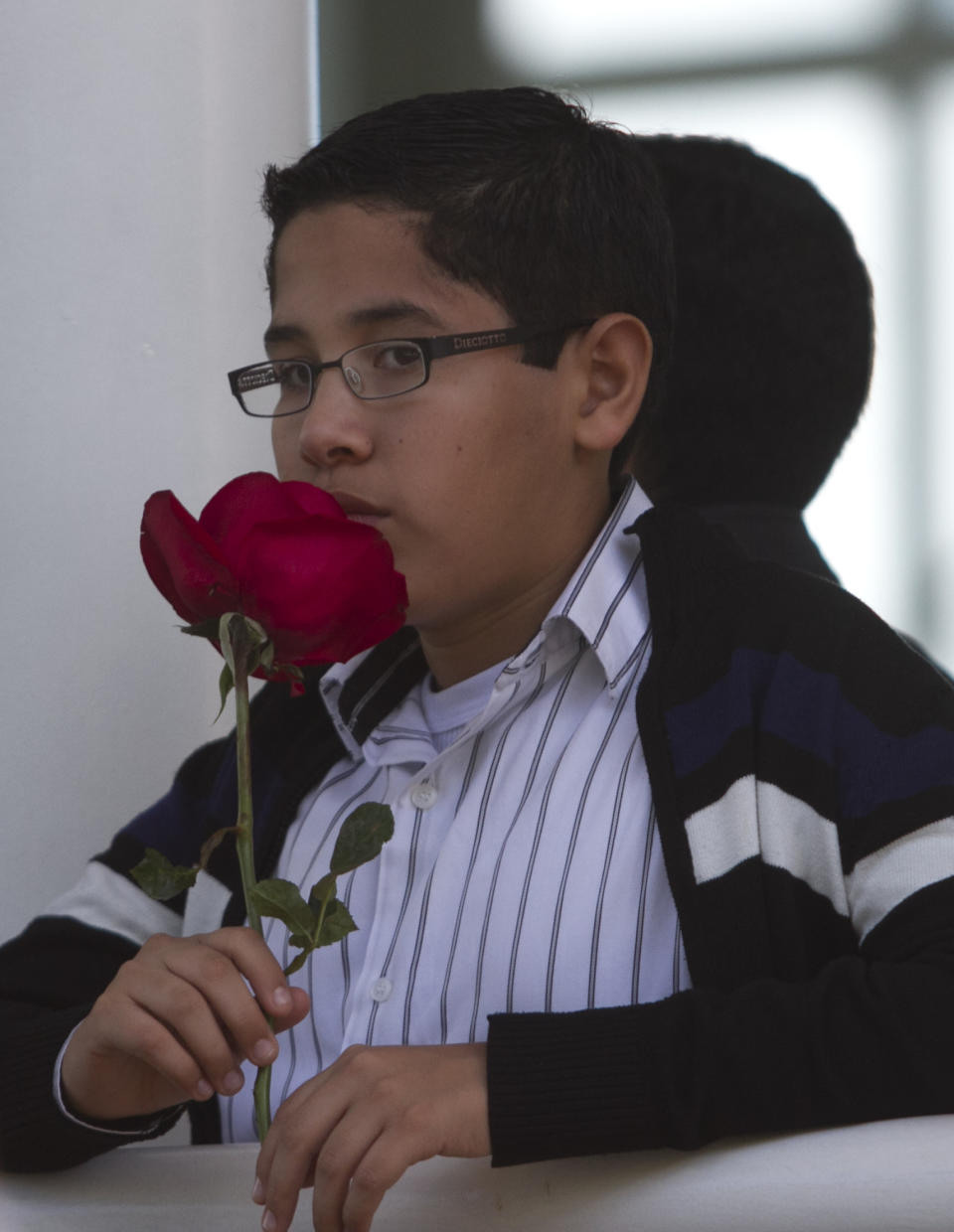 A boy holding a red rose stands outside the East cemetery chapel where a closed memorial service was held for Monica Spear, a popular soap-opera actress and former Miss Venezuela, in Caracas, Venezuela, Thursday, Jan. 9, 2014. Assailants shot and killed Spear and her Irish ex-husband, Henry Thomas Berry, in the presence of their 5-year-old daughter when they resisted a robbery, authorities said. Spear and Berry were slain by the assailants late Monday night on a roadside near Puerto Cabello, Venezuela's main port, after their car broke down. (AP Photo/Alejandro Cegarra)