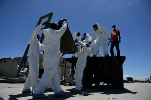 Hands and face protected by latex gloves and masks, the recovery team hoists bodies onto an old flatbed truck alongside other victims