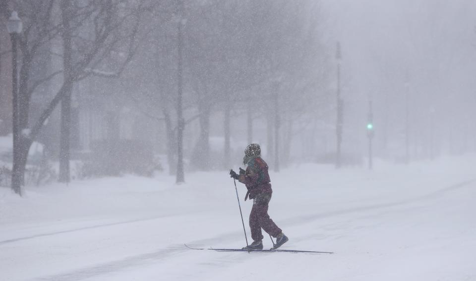 A skier crosses the street during a snowstorm in Quebec City